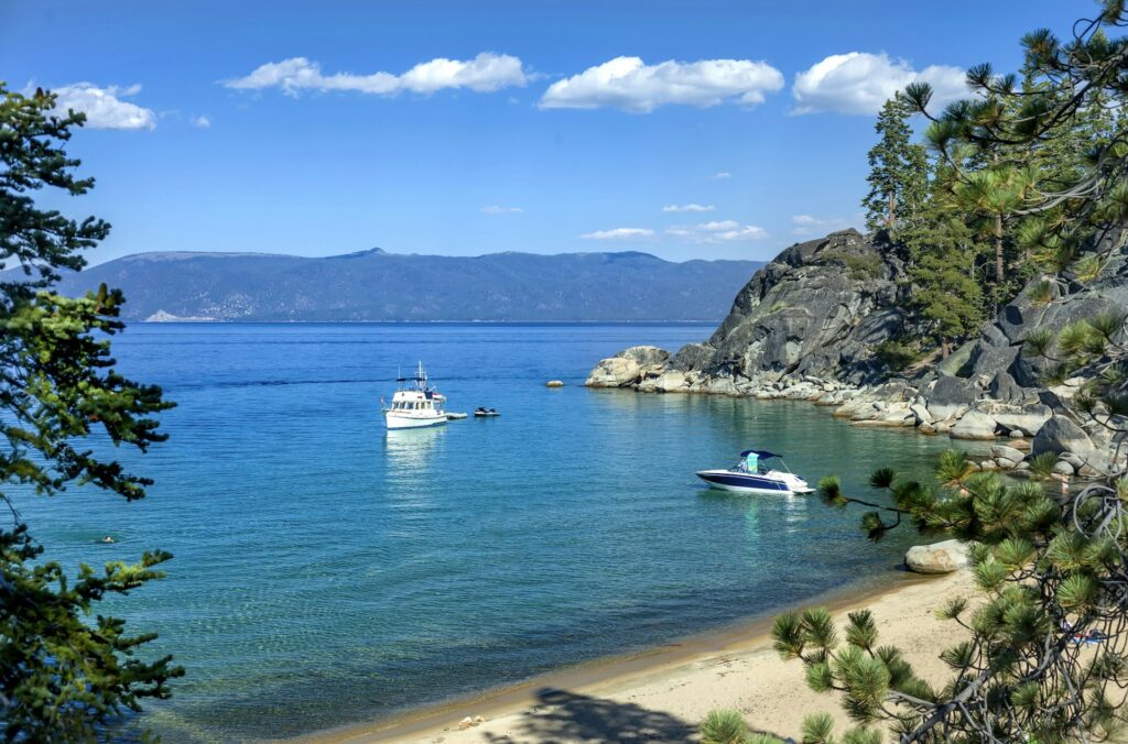Boats anchored off a wooded, rocky point on Lake Tahoe